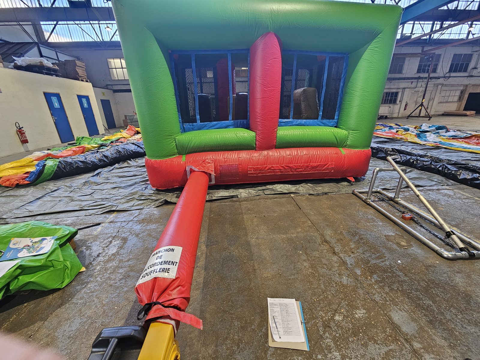 Structure gonflable verte et rouge installée dans l’entrepôt pour le contrôle, avec son manchon de soufflerie