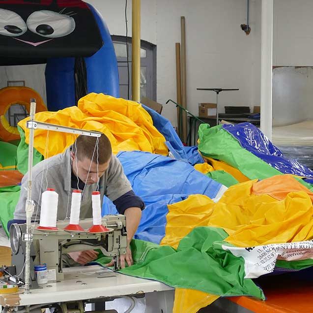 Atelier de réparation d’Air et Volume : un opérateur coud une toile de structure gonflable à la machine